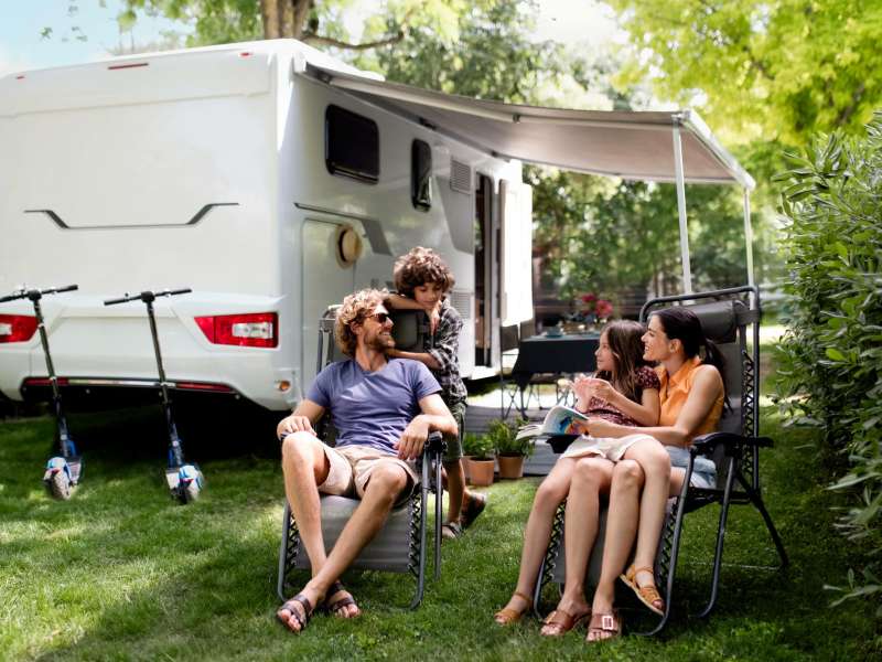 Familie genießt die frische Luft vor ihrem Wohnmobil auf dem Campingplatz