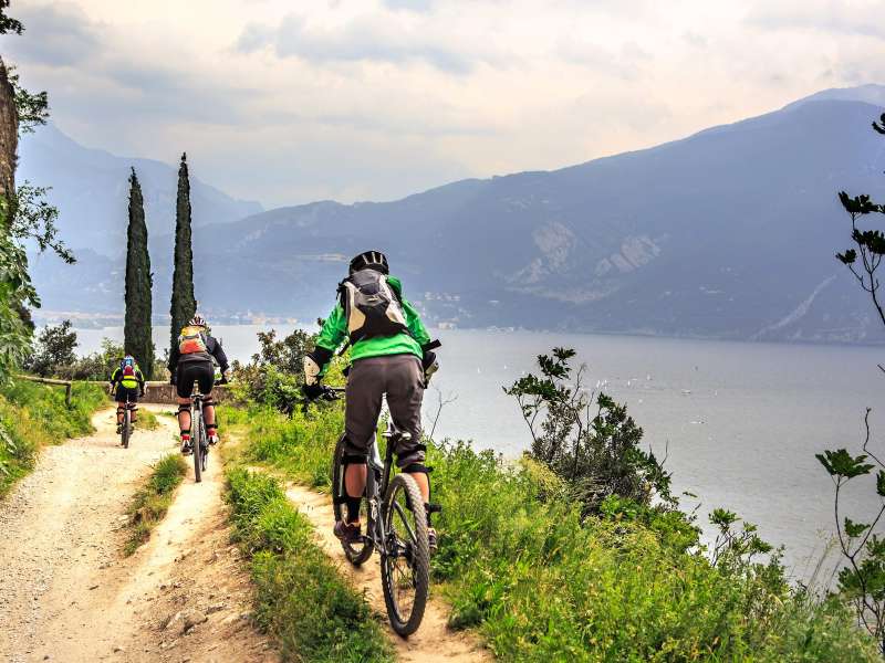 Personen beim Mountainbiken mit dem Gardasee im Hintergrund