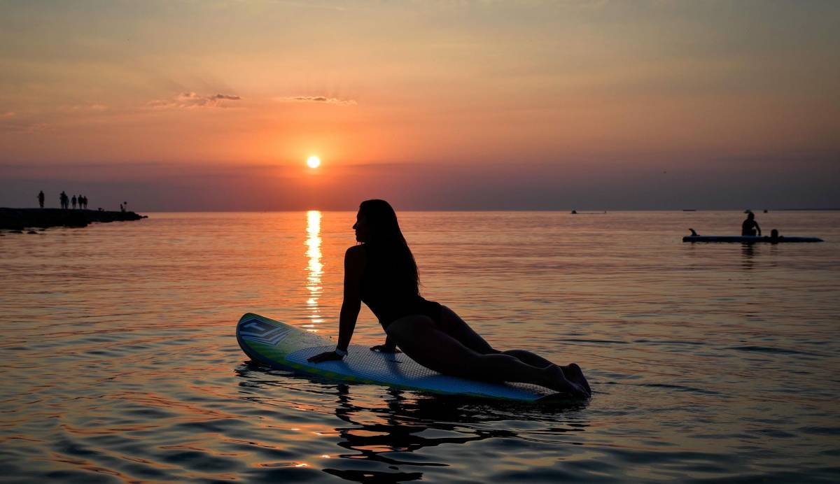 Mädchen praktiziert SUP Yoga auf dem Gardasee