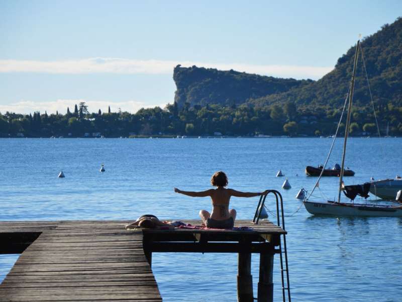 Frau beim Yoga auf dem Steg von Europa Silvella am Gardasee